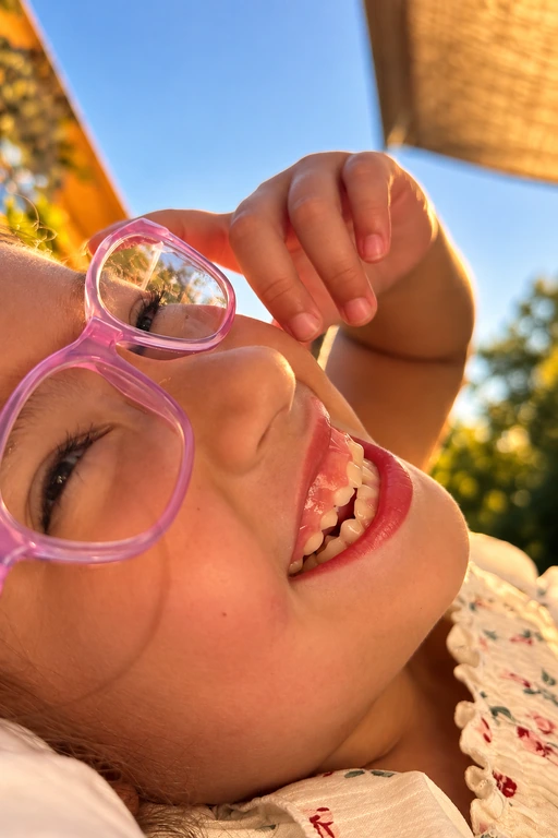 Kathleen smiling in the sunshine, wearing pink glasses.